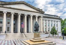 Government building with statue and American flag outside.