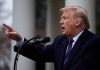 Man speaking at podium outdoors gesturing with hand