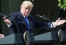 Man gesturing at two podiums outdoors.