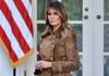 Woman in brown coat near American flag.