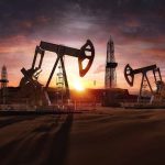 Oil rigs operating at sunset in a desert landscape.