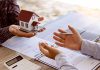 Two people discussing real estate contract with model house