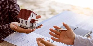 Two people discussing real estate contract with model house