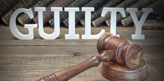 Judge's gavel and GUILTY sign on wooden table