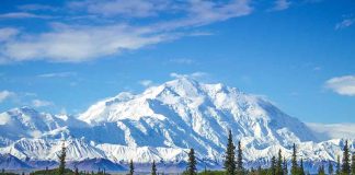 Snowcovered mountain under blue sky with green foreground