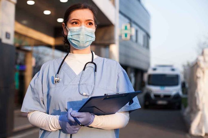 1714681855 featured image Nurse in scrubs and mask outside hospital holding clipboard