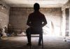 Person tied to chair in dimly lit room
