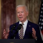 Man speaking at a podium with microphones.