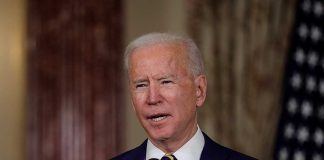 Man speaking at a podium with microphones.