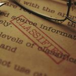 Classified document with glasses and pen closeup