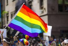 People holding and waving a rainbow flag