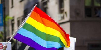 People holding and waving a rainbow flag