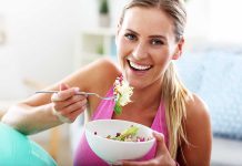 Woman smiling eating salad with fork indoors