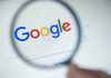 Google logo viewed through a magnifying glass