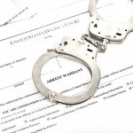 Handcuffs placed on an arrest warrant document