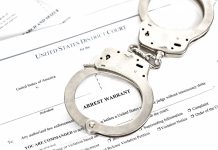Handcuffs placed on an arrest warrant document
