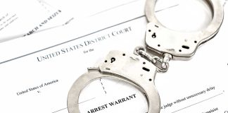 Handcuffs placed on an arrest warrant document