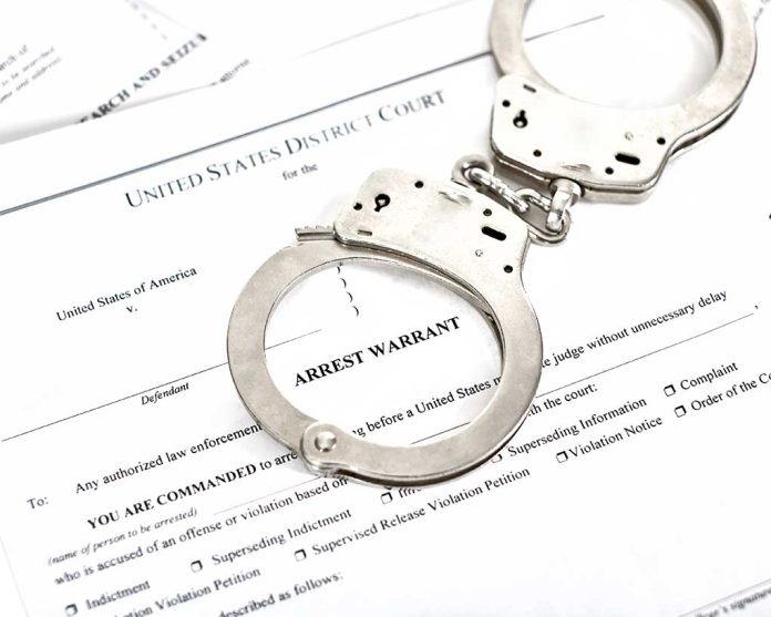 1316784506 featured image Handcuffs placed on an arrest warrant document