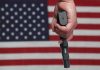 Hand holding gun against American flag backdrop