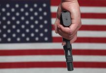 Hand holding gun against American flag backdrop