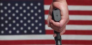 Hand holding gun against American flag backdrop