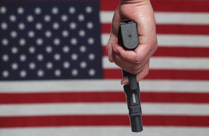 141984028 featured image Hand holding gun against American flag backdrop