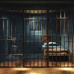 Empty prison cell with metal bars and bed