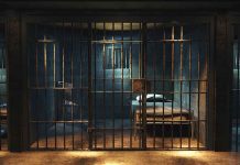 Empty prison cell with metal bars and bed