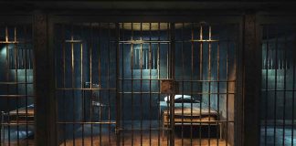 Empty prison cell with metal bars and bed