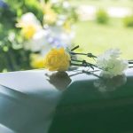 Yellow and white flowers on a green casket