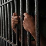 Hands gripping jail cell bars
