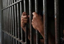 Hands gripping jail cell bars