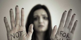 Handcuffed woman shows "NOT FOR SALE" on her palms.