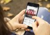 Person holding smartphone displaying fake news notification