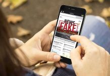 Person holding smartphone displaying fake news notification