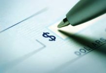 Close up of a pen poised over a check with a dollar sign
