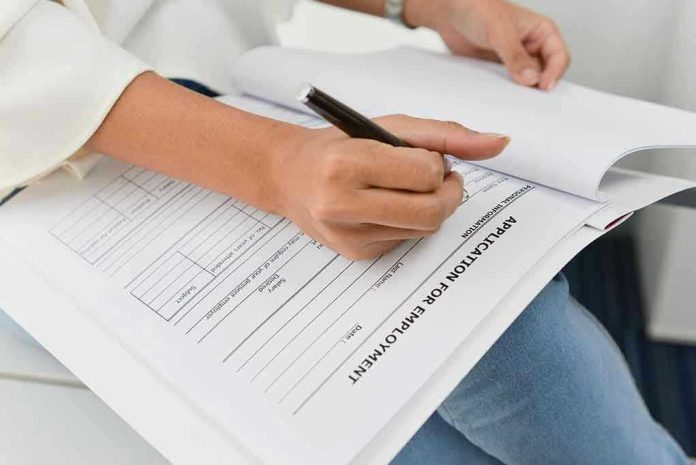 420099925 Person filling out job application form.