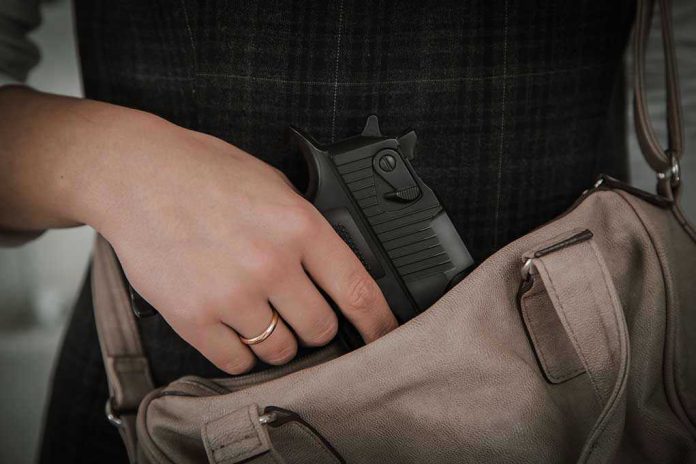 427035313 Hand placing handgun into beige handbag.