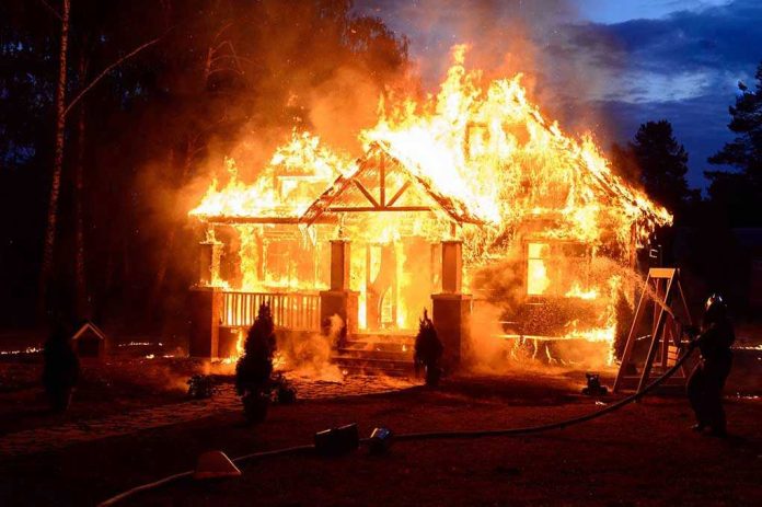 569622439 House engulfed in flames with firefighters present