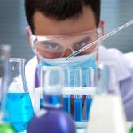 Scientist conducting an experiment with blue liquids in a laboratory