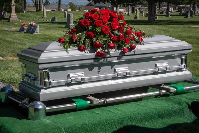175194851 Silver casket with red roses in a cemetery.