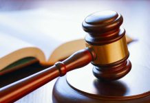 Gavel resting on sounding block beside open book.