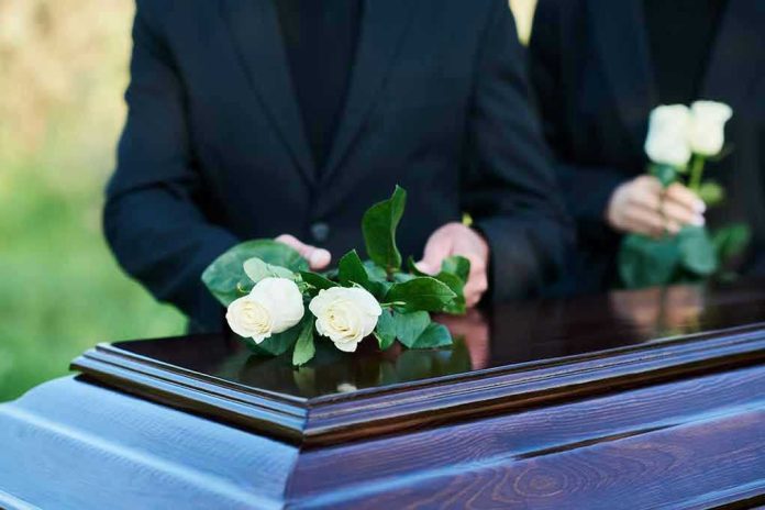 2360876213 People placing white roses on a casket.