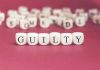 Dice spelling GUILTY on a red surface.
