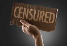 A hand holding a cardboard sign that reads 'CENSORED'