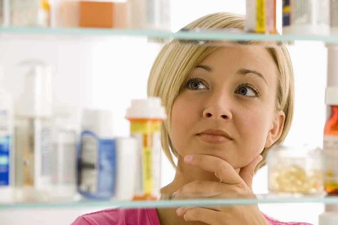 shutterstock_57590812.jpg A woman thoughtfully looking at a medicine cabinet filled with various medications
