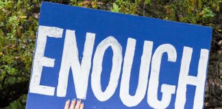 Hands holding blue sign saying enough