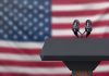 White House Staffer CRUSHES Reporter – Brutal! Podium with microphones in front of American flag.