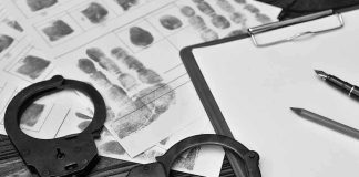 Fentanyl Kingpin SNATCHED—Long Time COMING! Handcuffs, fingerprint sheets, and clipboard on a desk.