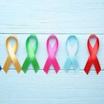 Cancer’s Worst Nightmare Just Got FDA Approval Colorful awareness ribbons on light wooden background.